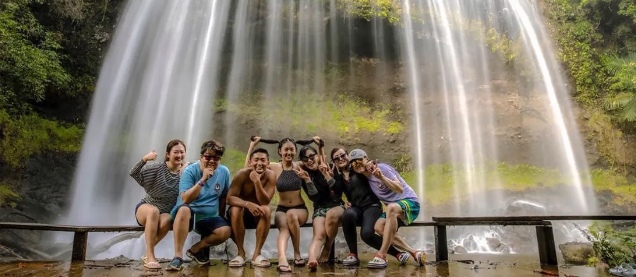 Group of tourists having fun in front of an 18 meter high waterfall in Palau