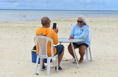 2 people sitting on chairs with table at the Airai sandbank in Palau